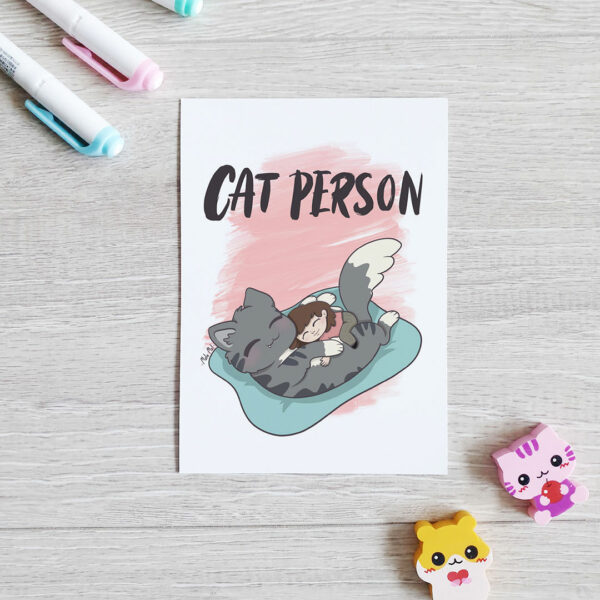 Die Postkarte "Cat Person" zeigt eine junge Frau, die mit einer riesigen liegenden Katze kuschelt.